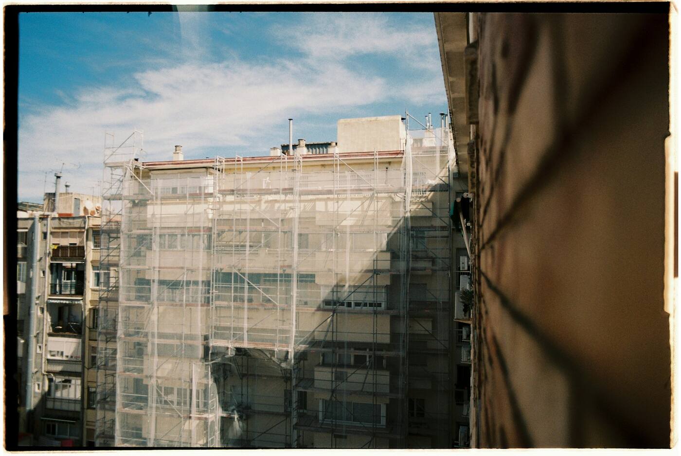 Edificio de viviendas cubierto con andamio y malla protectora