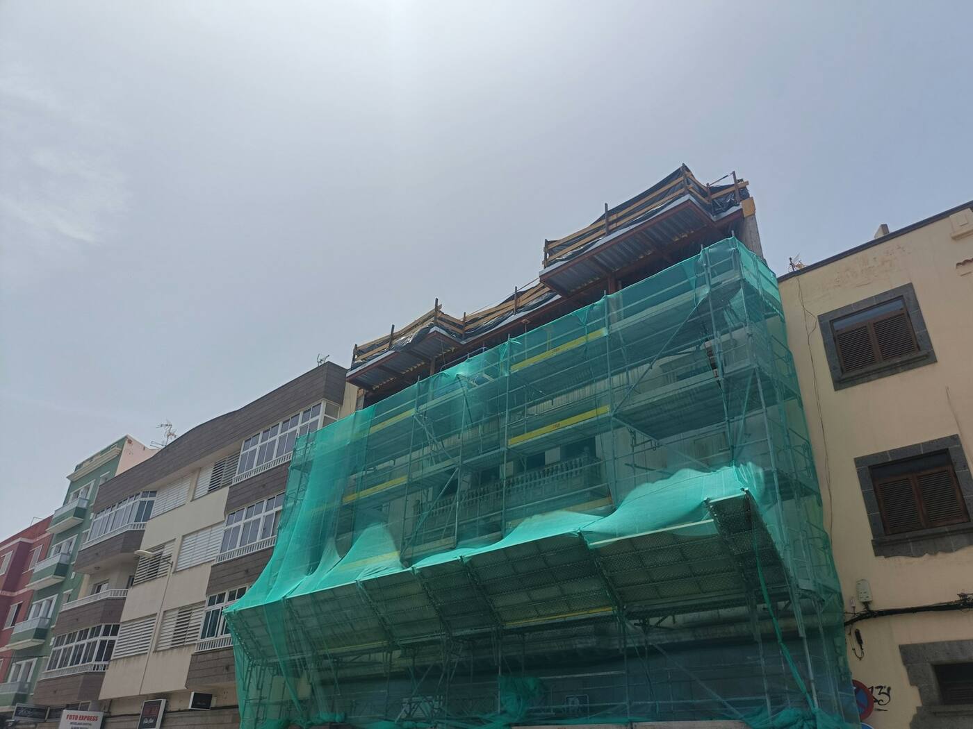 Edificio en rehabilitación con andamio y malla de protección